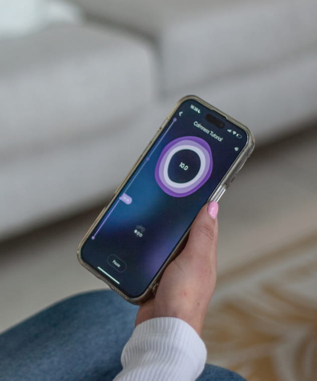  A woman holding a phone using Oxa breathing coach app for improved stress management and calmness